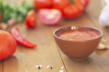 Red chili sauce with ingredients on wooden table