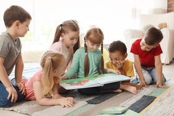 Cute little children reading book together indoors. Learning by playing