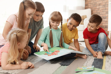 Cute little children reading book together indoors. Learning by playing