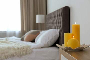 Burning candles on bedside table in bedroom