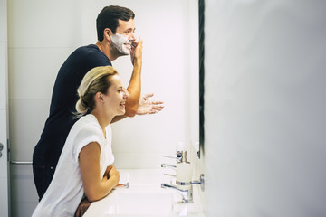 happy couple at home enjoy lifestyle in the bathroom. young beautiful man doing and cutting the...