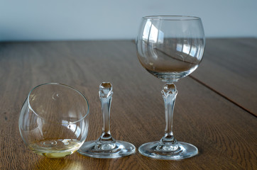 Two wine glasses. One half full broken glass and empty undamaged wine glass on wooden table