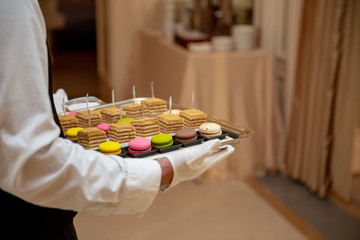 The waiter serves an expensive dessert of macaroons