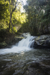 Small waterfall found in the beautiful forest of Mae Klang Luang. Chiang Mai, Thailand. Sun shining through the foliage.