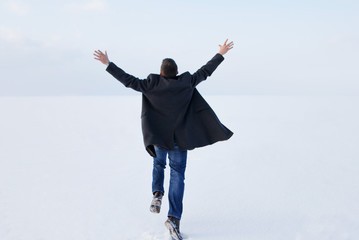 man standing on the shore of a frozen sea downshifting way relaxes on a winter seascape