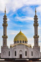 White Muslim mosque with golden domes on a bright day