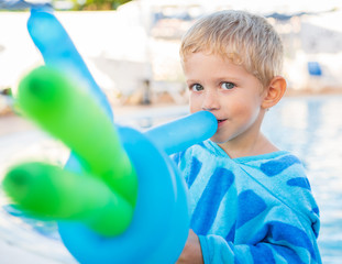 beautiful child plays with balloons at the edge of the pool, sunny day,close up.
