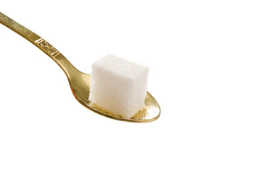 Ein Stück Würfelzucker in goldenem Kaffeelöffel