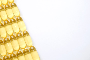 Bunch of omega 3 fish liver oil capsules in row forming pattern background. Close up of big golden...
