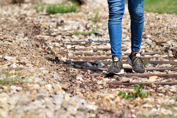 Young handsome guy walking along old railway, enjoying his surroundings on sunny day. Traveler man on railroad. Following the old railway trail. Contemplating a trip by train. City style. Adventure.