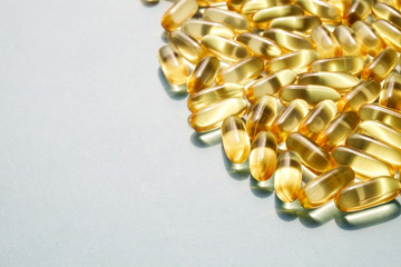 Bunch of omega 3 fish liver oil capsules in pile forming pattern background. Close up of big golden...