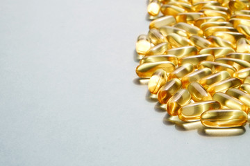 Bunch of omega 3 fish liver oil capsules in pile forming pattern background. Close up of big golden...