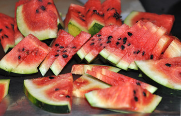 Slices, pieces of ripe watermelon are laid out on a platte