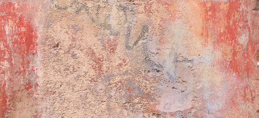 Old weathered painted wall background texture. Red dirty peeled plaster wall with falling off flakes of paint.