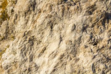 Naklejka premium The texture of the stone wall of the rock with multi-colored shades, cracks, chips, scratches and small stones.