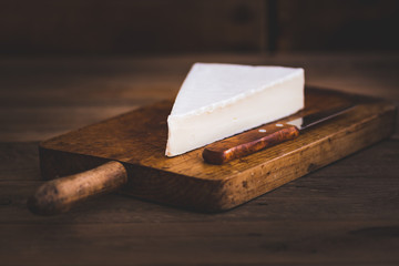 portion of brie cheese camenbert on wood cutting board