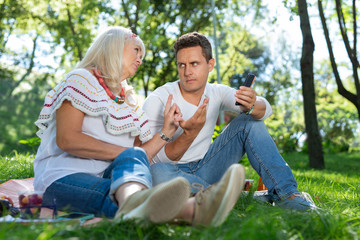 Fototapeta premium Do not agree. Cheerful blonde crossing legs while sitting on the grass