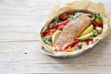 Fish and vegetables. Oven baked sesame salmon  with roasted vegetables, lemon and herbs.  Selective focus