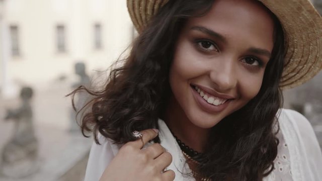 Close up view of lovely curly woman with beautiful necklace, earrings and braclets in stylish outfit smiling happily smiling to camera. Natural beauty, seductive, hot