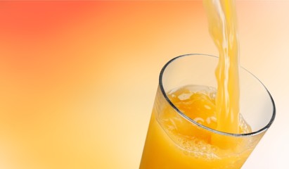Orange juice pouring in glass on background