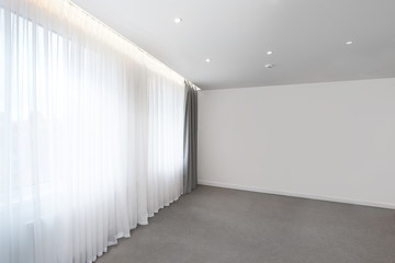 Empty room with white curtains on a window