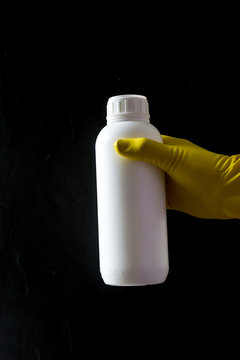 White plastic bottle with pesticides on a black background.
