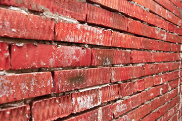 part of a wall of red dirty brick spattered with cement