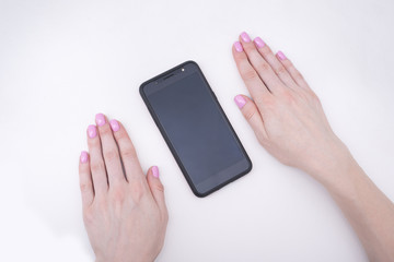 Gentle pink manicure. Female hands with a smartphone