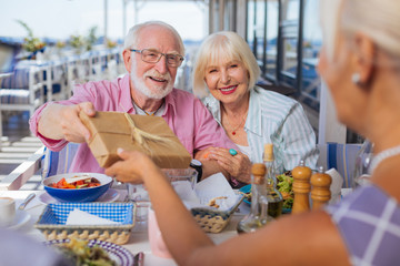 Happy birthday. Delighted aged people sitting together at the table while having a celebration together