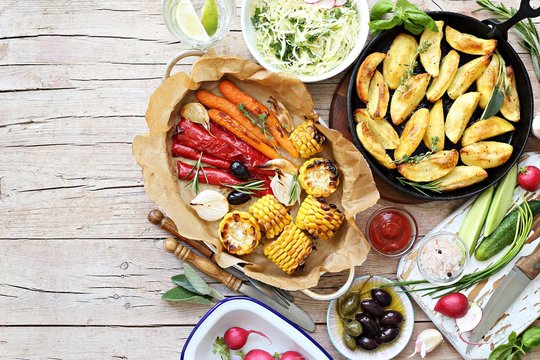 Food grilled vegetables outdoor table family dinner potato wedges roasted corn party picnic. Overhead view, copy space