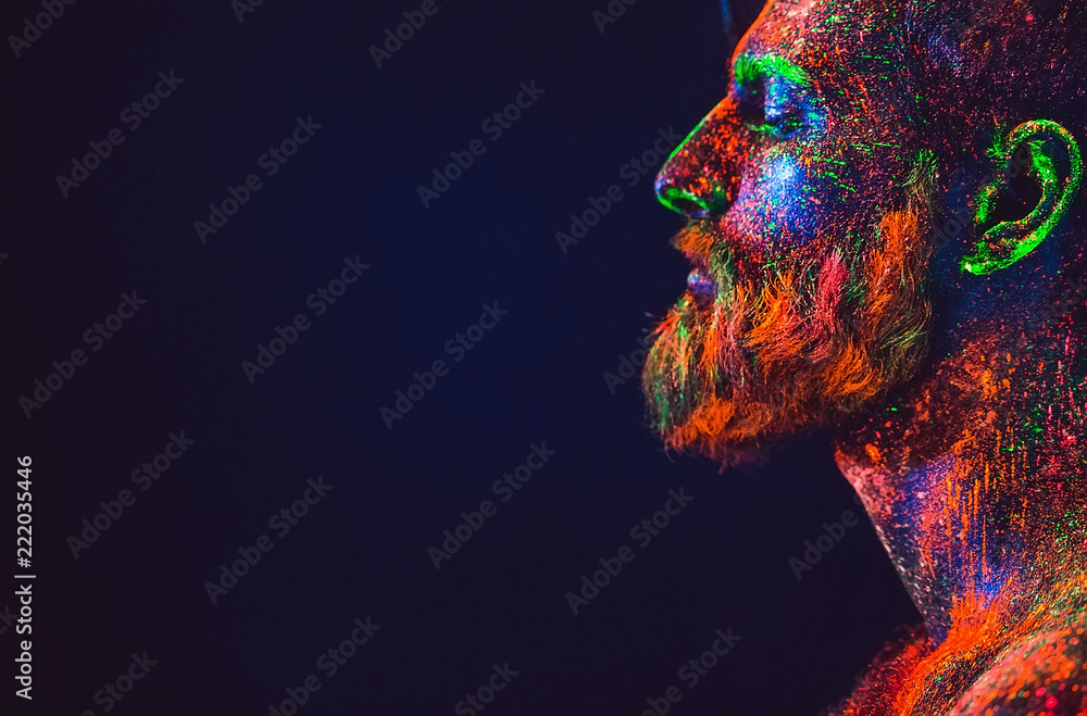 Wall mural concept. portrait of a bearded man. the man is painted in ultraviolet powder.