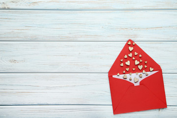 Small brown hearts with red envelope on wooden table