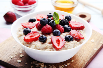 Oatmeal with berries in bowl on cutting board