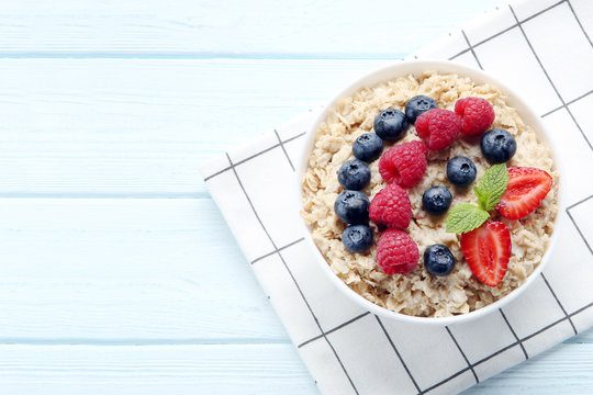 Oatmeal with berries in bowl on wooden table