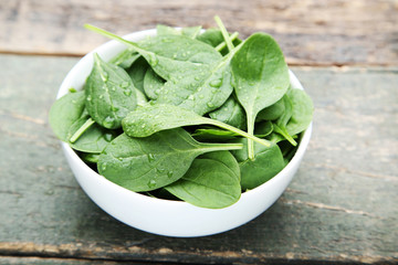 Spinach leafs in bowl on grey wooden table