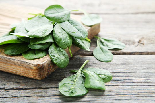 Spinach leafs with cutting board on grey wooden table