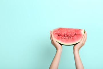 Female hands holding sliced of watermelon on mint background