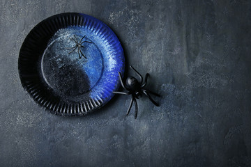 Black spiders with plate on grey wooden table