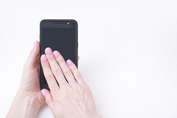 Gentle pink manicure. Female hands with a smartphone