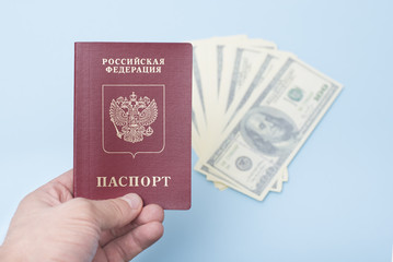 Russian international passport in the man's hand. Dollars. Blue background