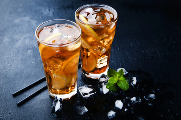 Ice tea in glasses with lemon and mint leafs on wooden table
