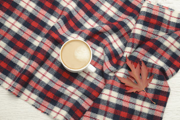 Cappuccino on checkered plaid, autumn leaf. Fashionable concept