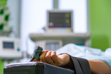 Patients hand with a sensor on the blurry background of the group of doctors in the operating room....