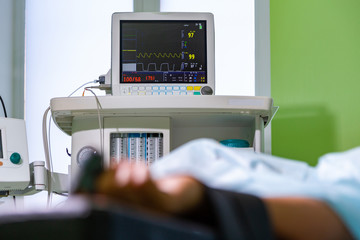 Patients hand with a sensor on the blurry background of the group of doctors in the operating room. Close up, Selective focus