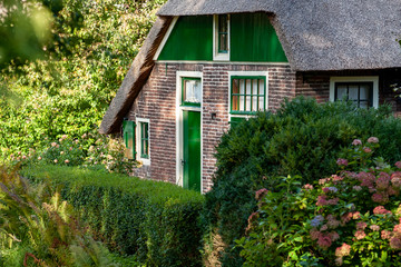Fototapeta na wymiar Landscape view of Giethoorn, picturesque village with canals and rustic thatched roof houses in farm area in Holland