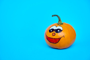 Funny Halloween concept. Cheerful pumpkin with smile face on a blue background