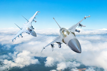 Fototapety  Para myśliwców bojowych na misji wojskowej z bronią - rakiety, bomby, broń na skrzydłach leci wysoko na niebie nad chmurami.