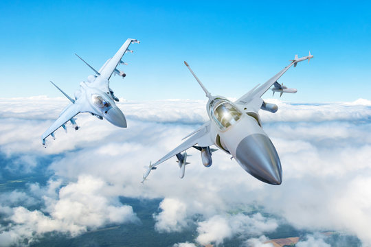 Fototapeta Pair of combat fighter jet on a military mission with weapons - rockets, bombs, weapons on wings flies high in the sky above the clouds.