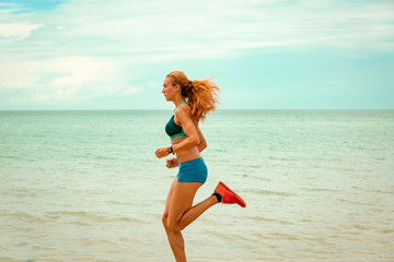 Naklejka premium Beautiful sportive woman running along beautiful sandy beach, healthy lifestyle, enjoying active summer vacation near the sea