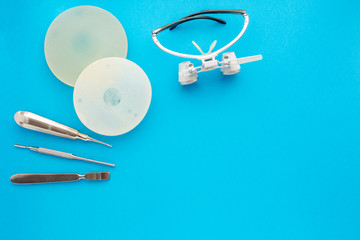 Medical equipments including surgical instruments and breast implants on a blue background. top view, copy spase